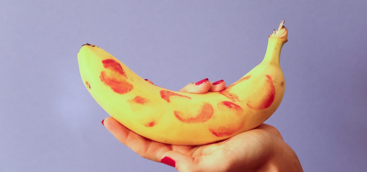 Person holding banana with lipstick marks on it