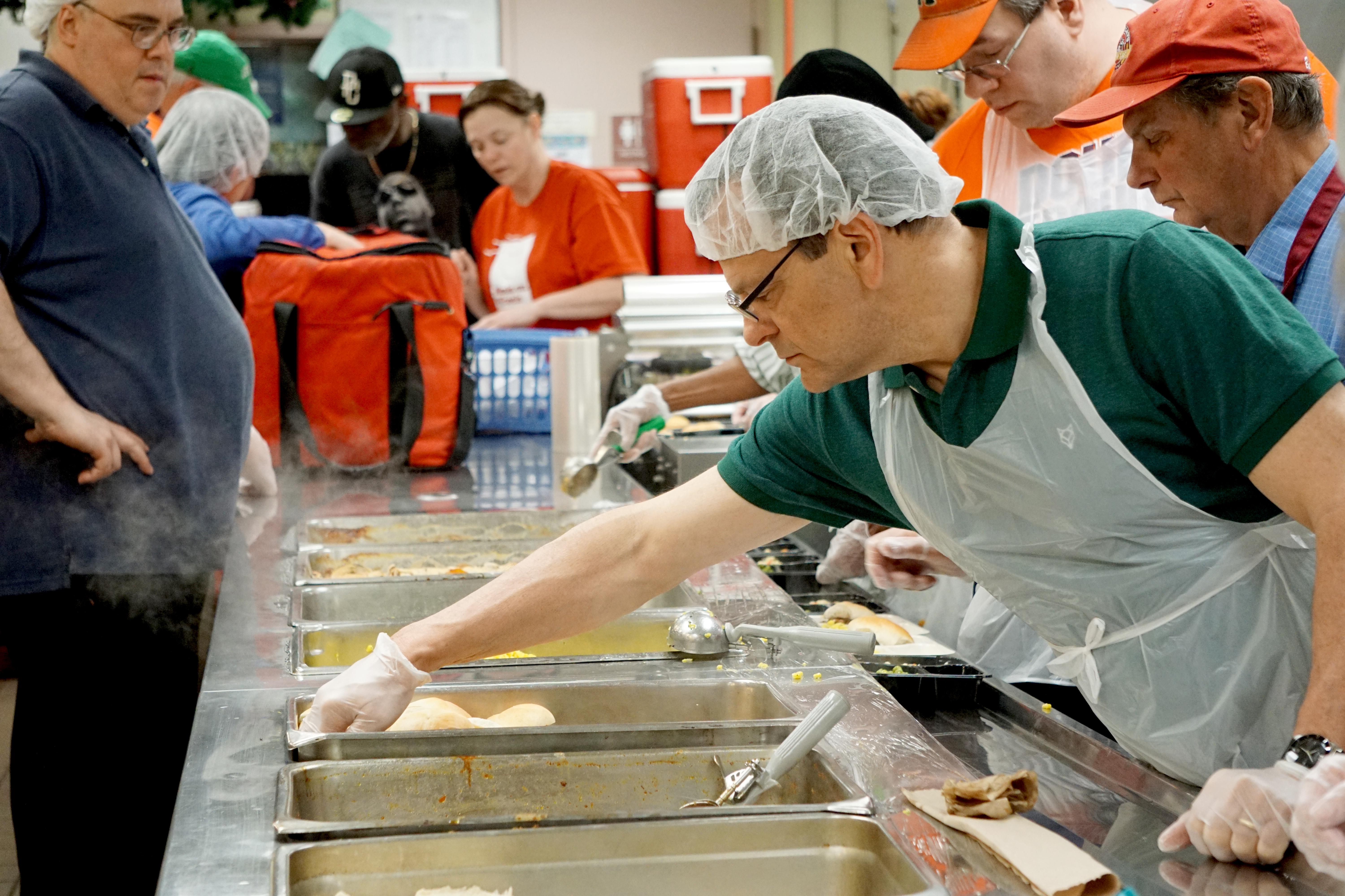 The food prep line at Meals on Wheels operates like a conveyer belt, Kaufman explains. Food service staff prepare the food earlier in the morning before the volunteers arrive. Then, different meal items are passed down the line and ultimately placed in their microwave- and oven-safe trays before being wrapped tightly with cellophane.